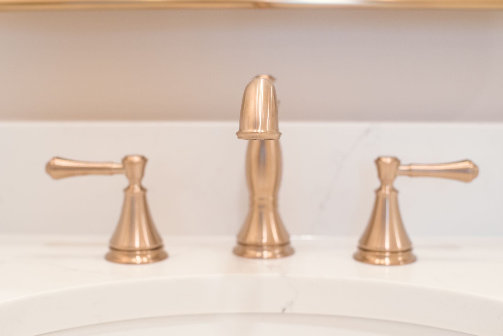 Gold bathroom faucet with two handles and a central spout on a white surface.