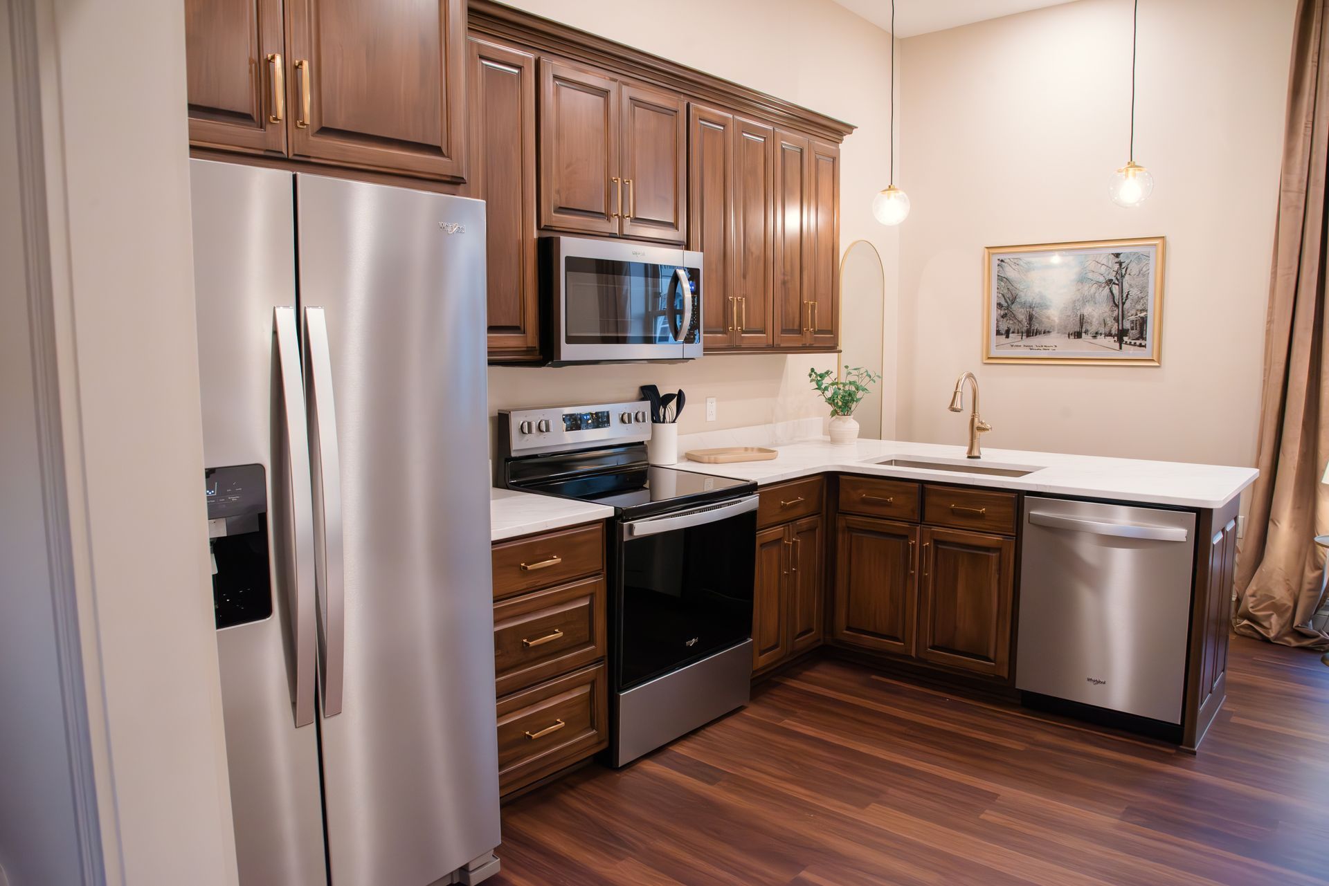 Stainless steel kitchen with dark wood cabinets, white countertops, and hardwood floor.