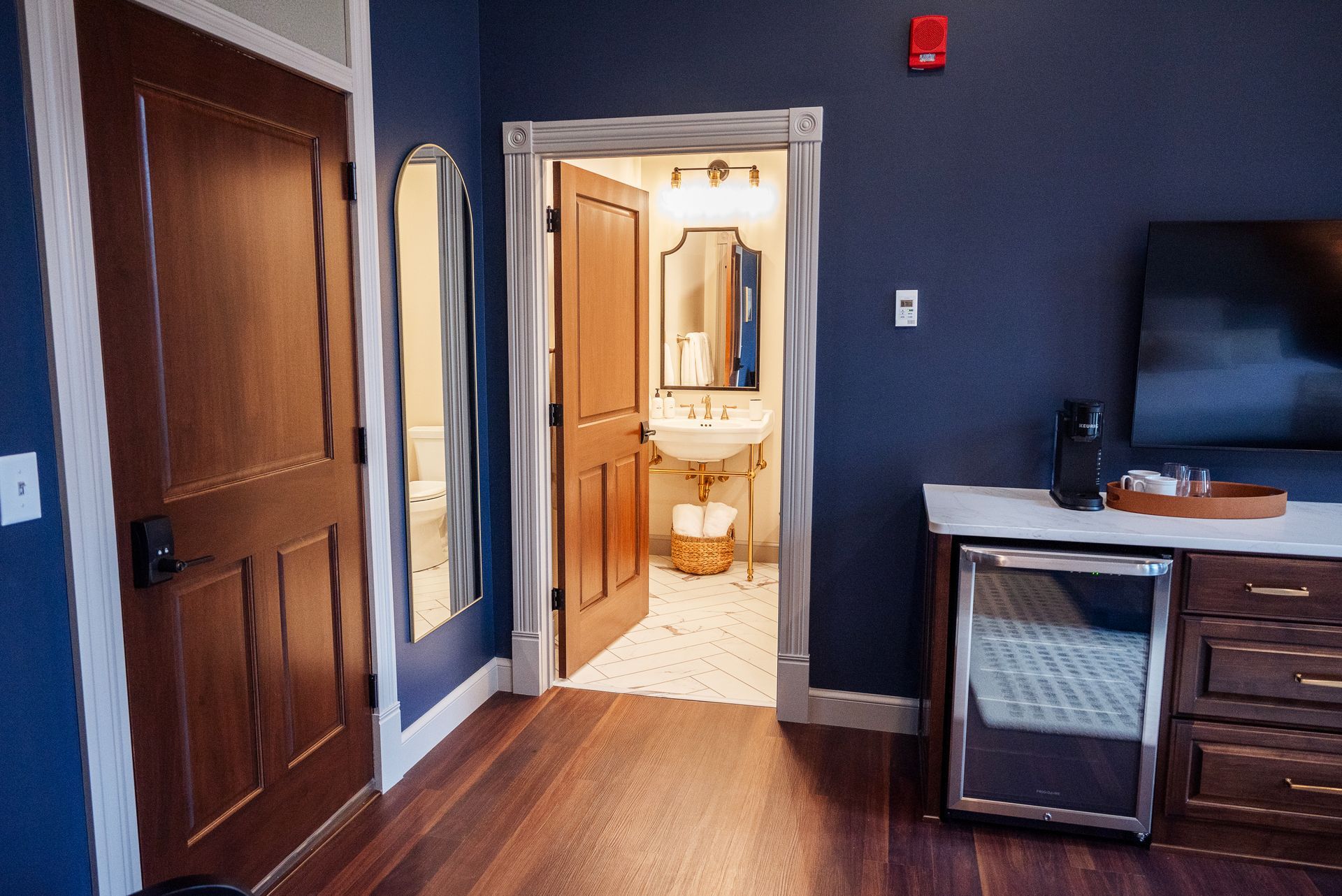 Hotel room interior with dark blue walls, wooden doors, and a glimpse of the bathroom.
