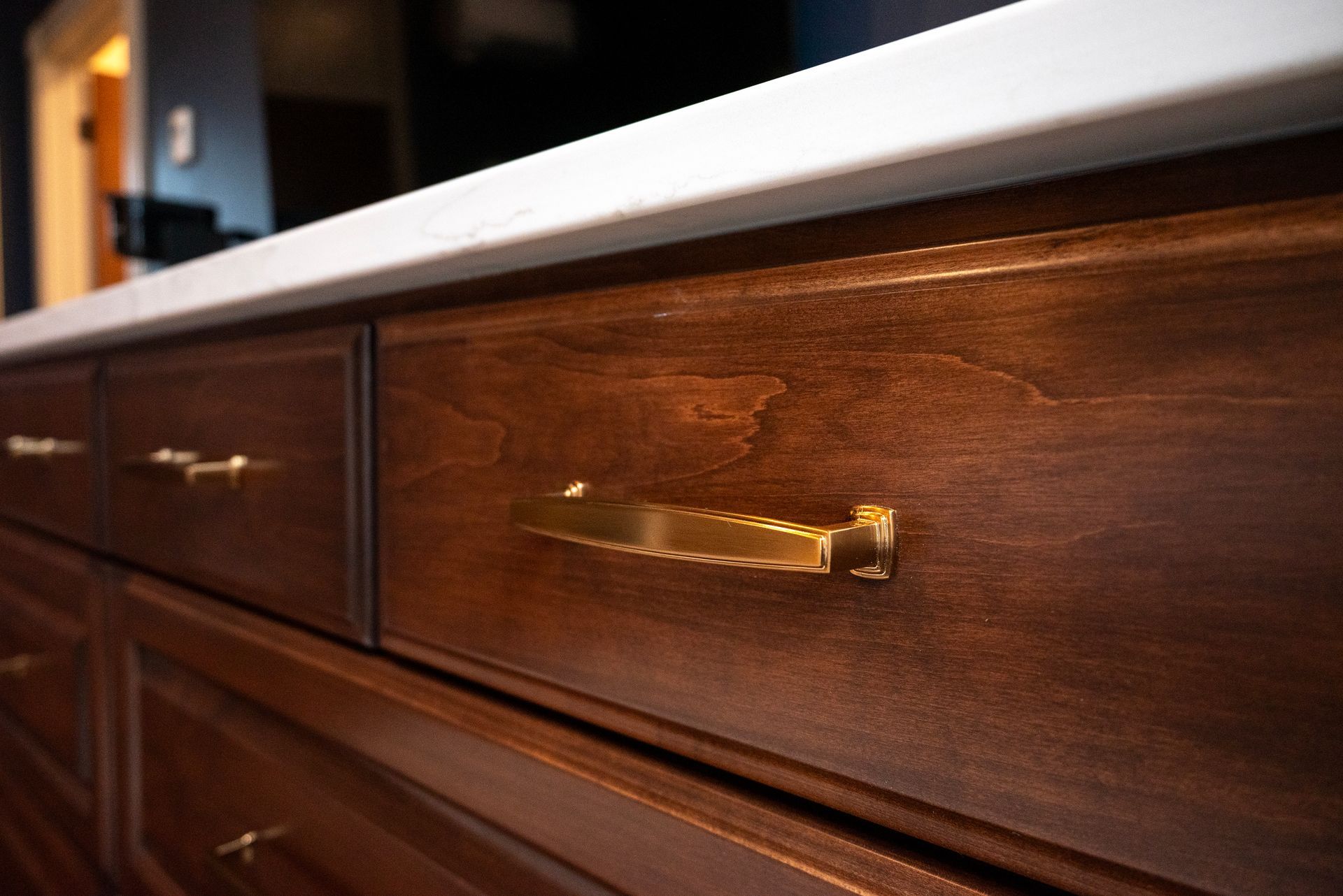 Dark brown kitchen cabinets with gold hardware, topped by a white countertop.