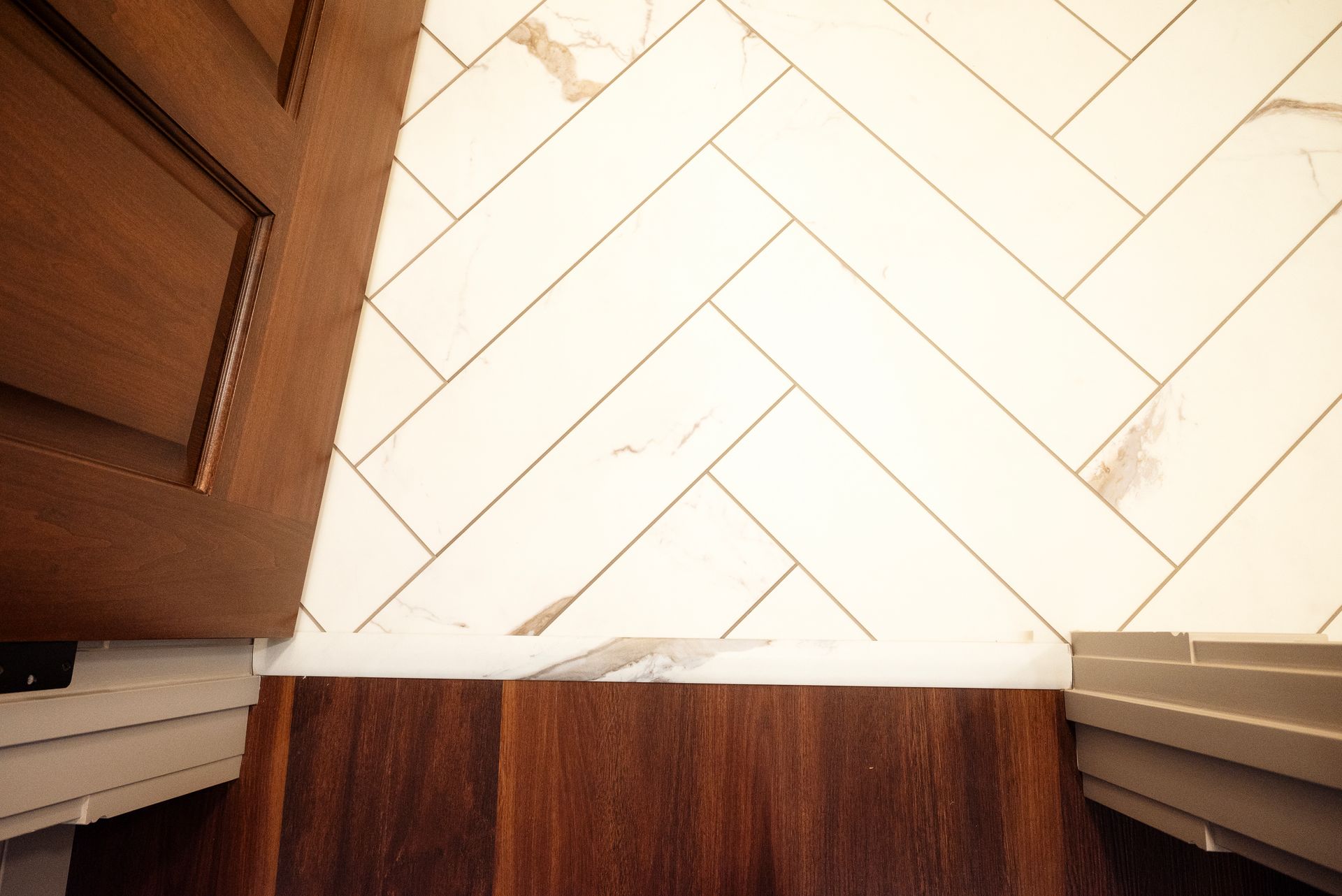 Doorway with dark wood floor and trim, light herringbone tile wall.