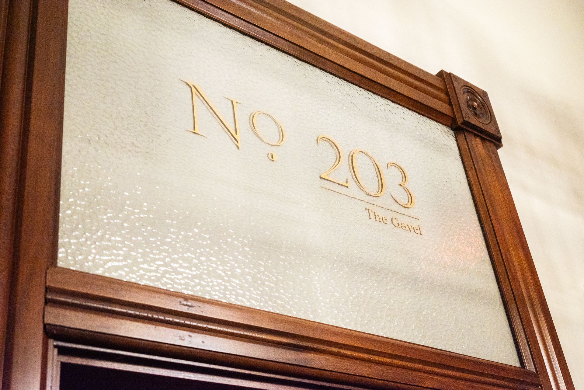 Wooden door with textured glass panel, gold lettering reads 