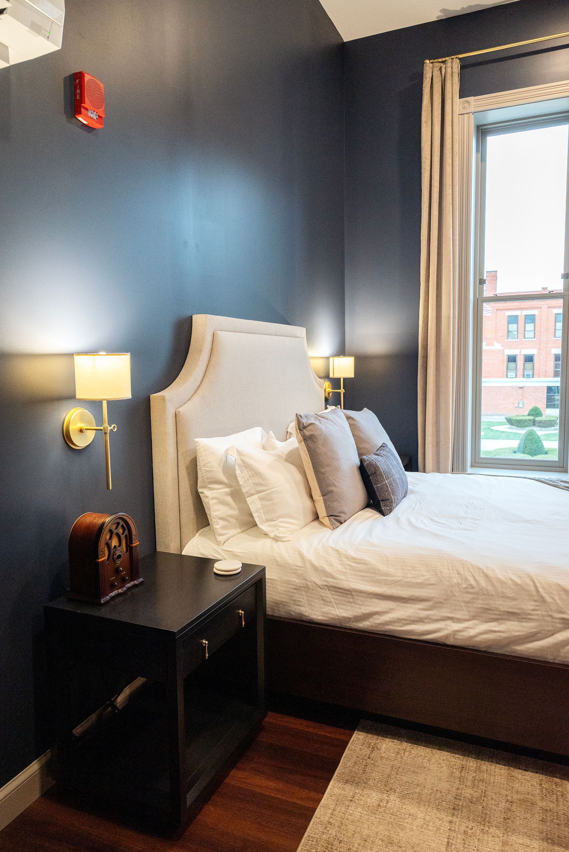 Bedroom with navy blue walls, a bed with white linens, and a nightstand.
