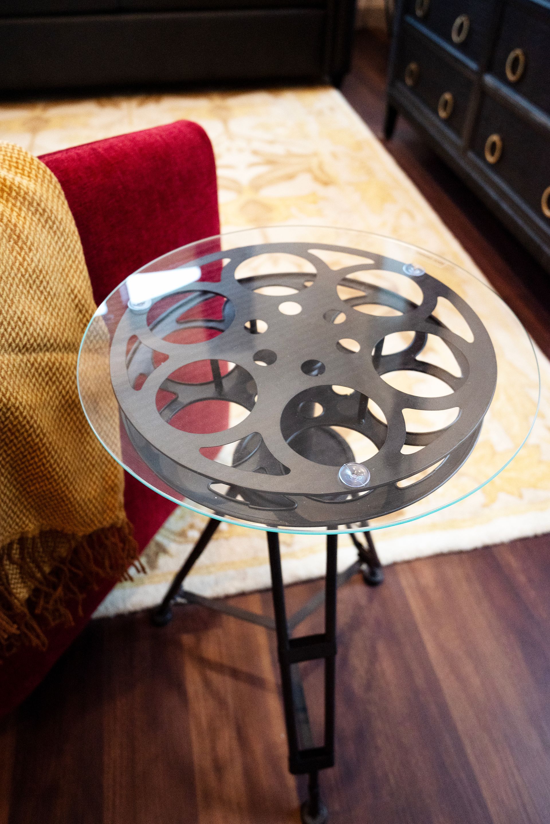 Round glass side table with a film reel design base.