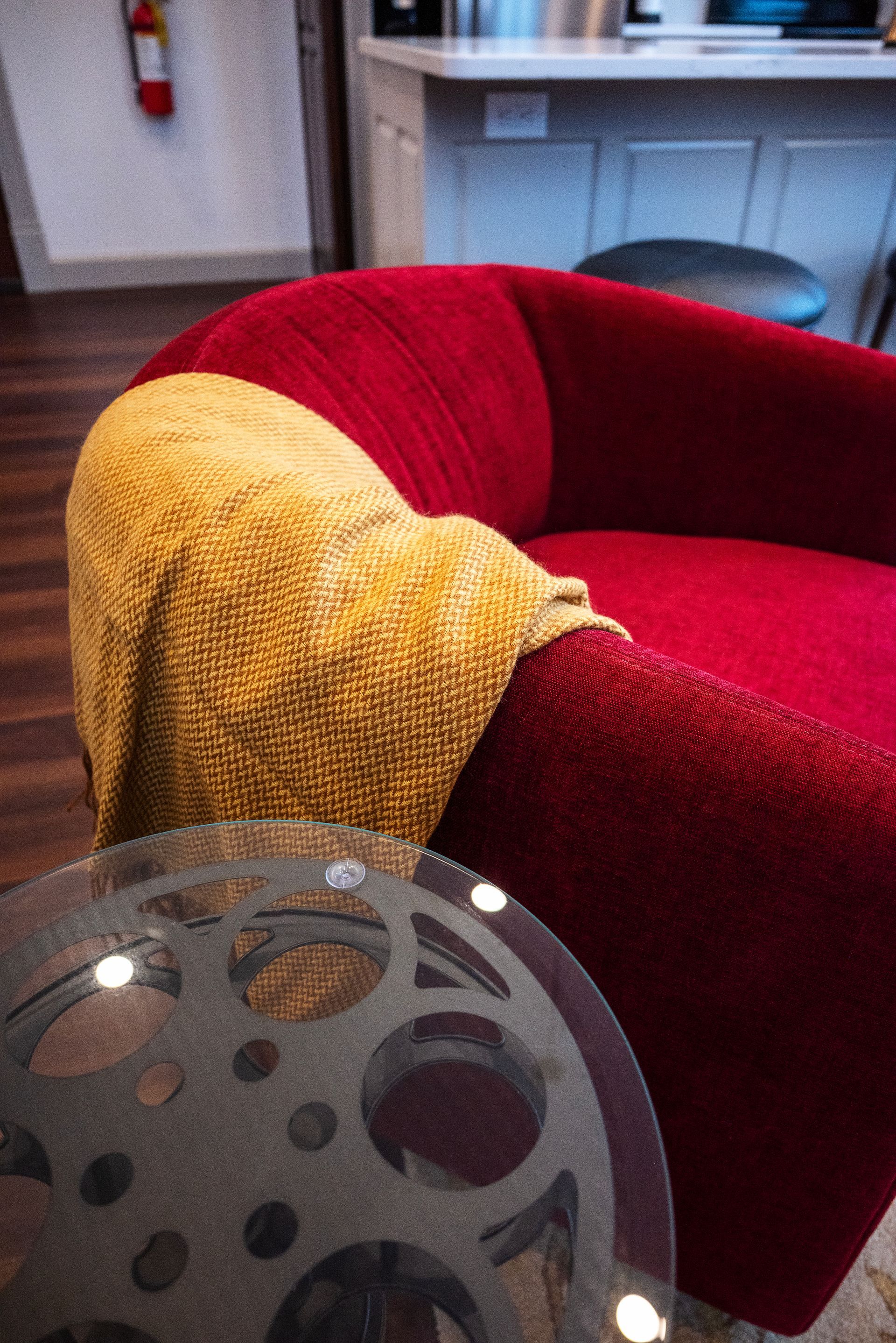 Red armchair with yellow blanket, near a glass-topped table.