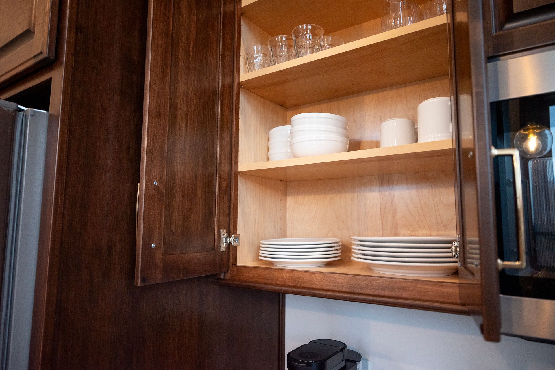 Open kitchen cabinet with dishware inside.