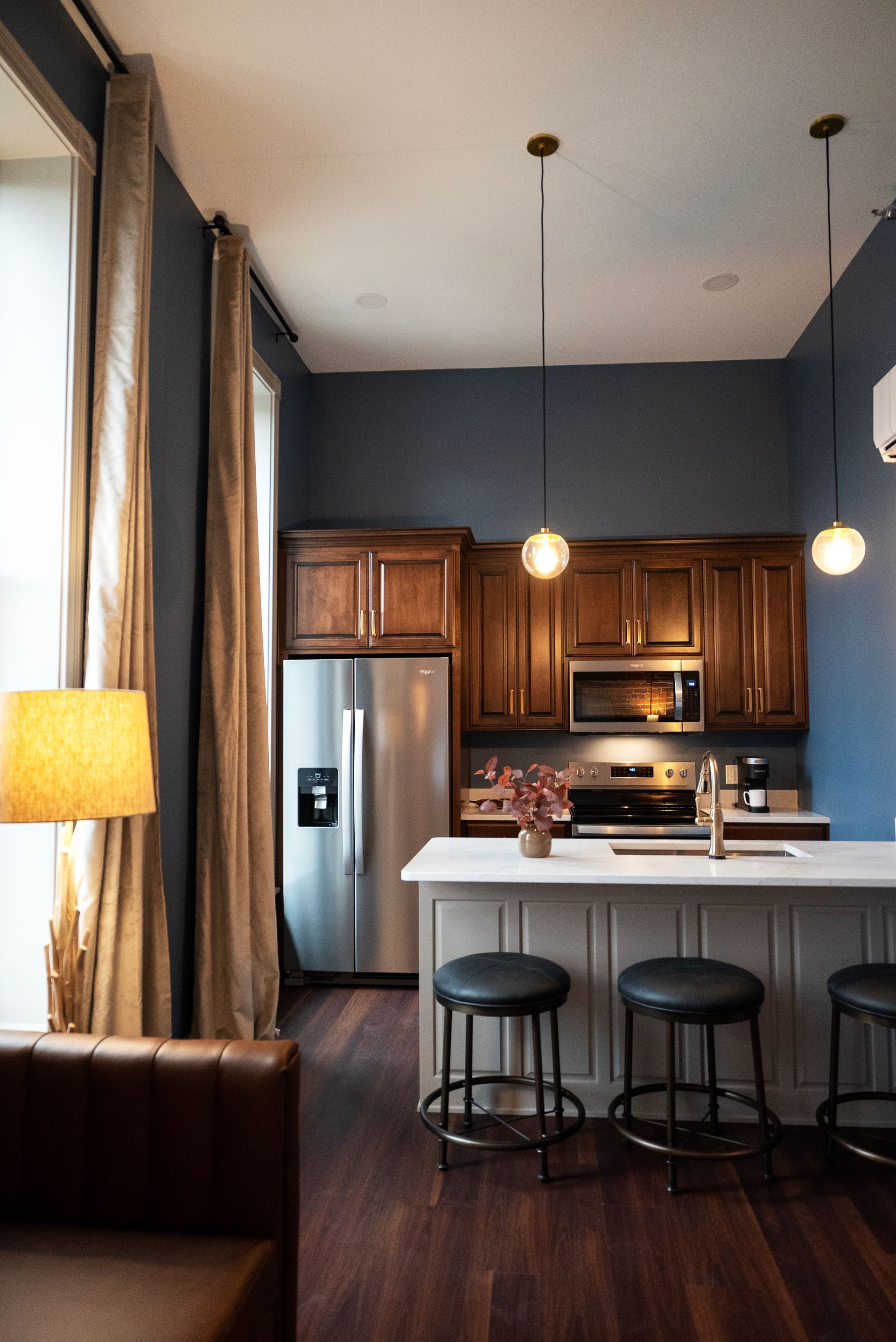Kitchen with dark wood cabinets, stainless steel fridge, and a gray and white island with stools.