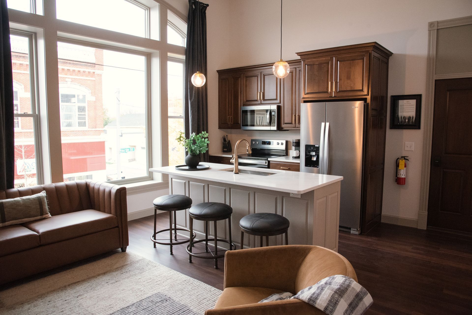 Kitchen area with brown cabinets, stainless steel appliances, and a white countertop island with bar stools.