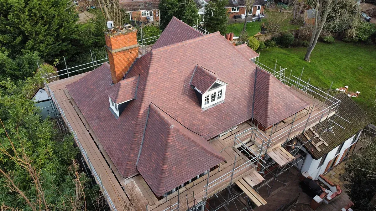 An aerial view of a house under construction with a red tile roof.