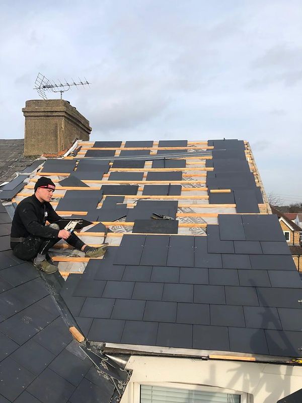 man on roof installing slate roofing