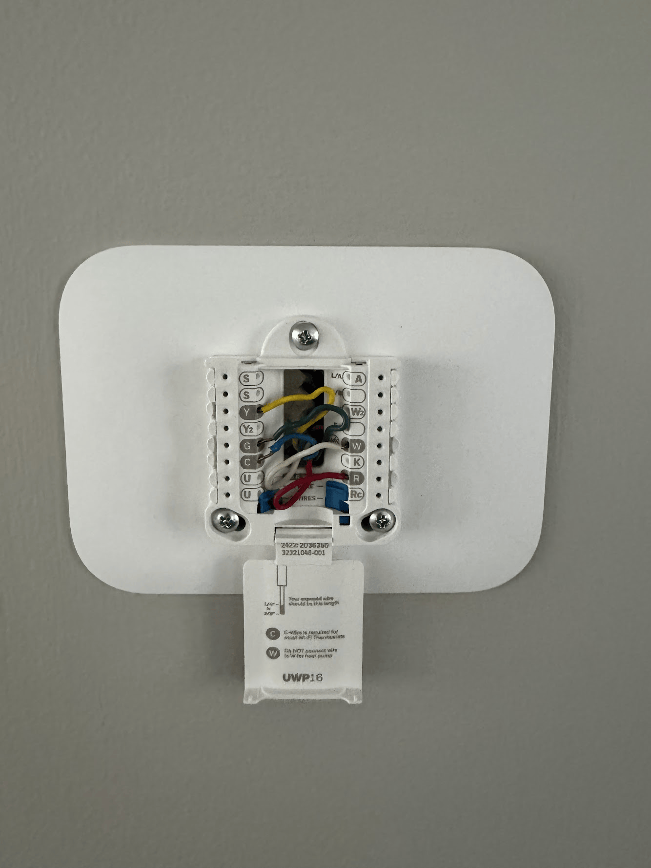 The back of a thermostat is shown with wires coming out of it.