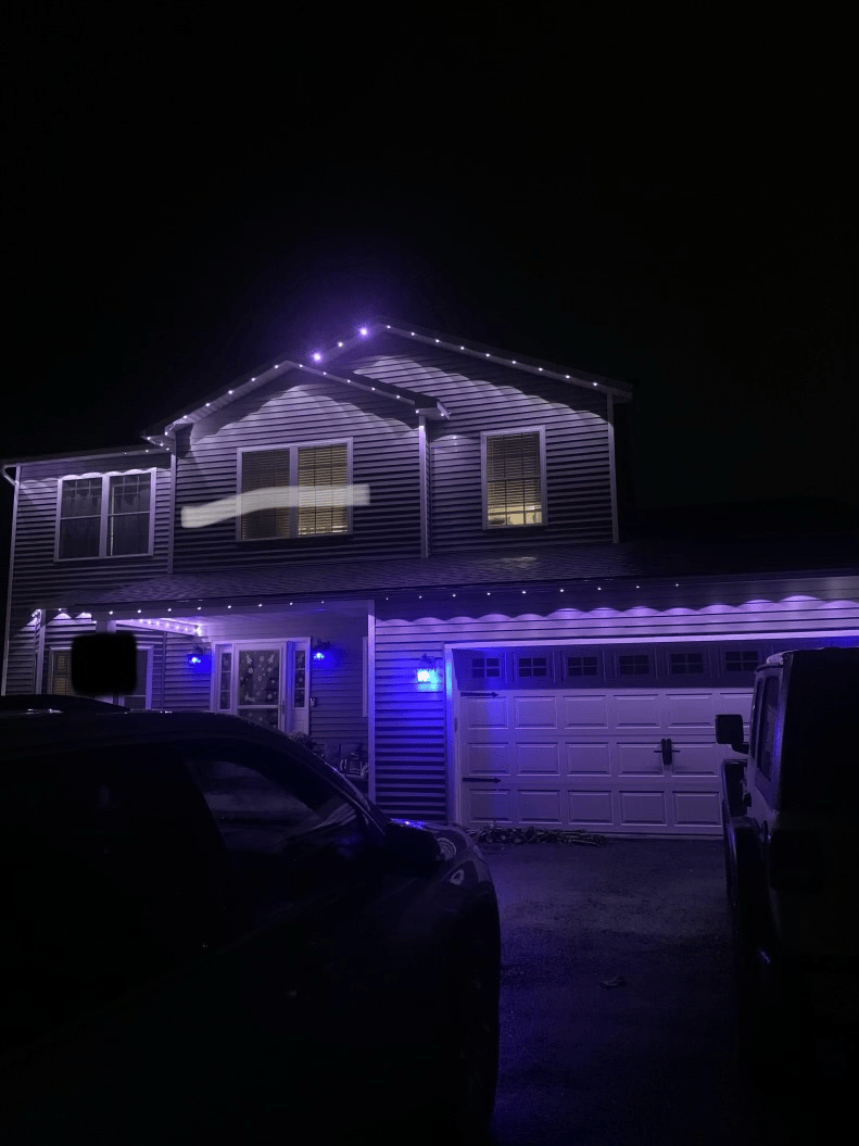 A house with purple lights on it is lit up at night.