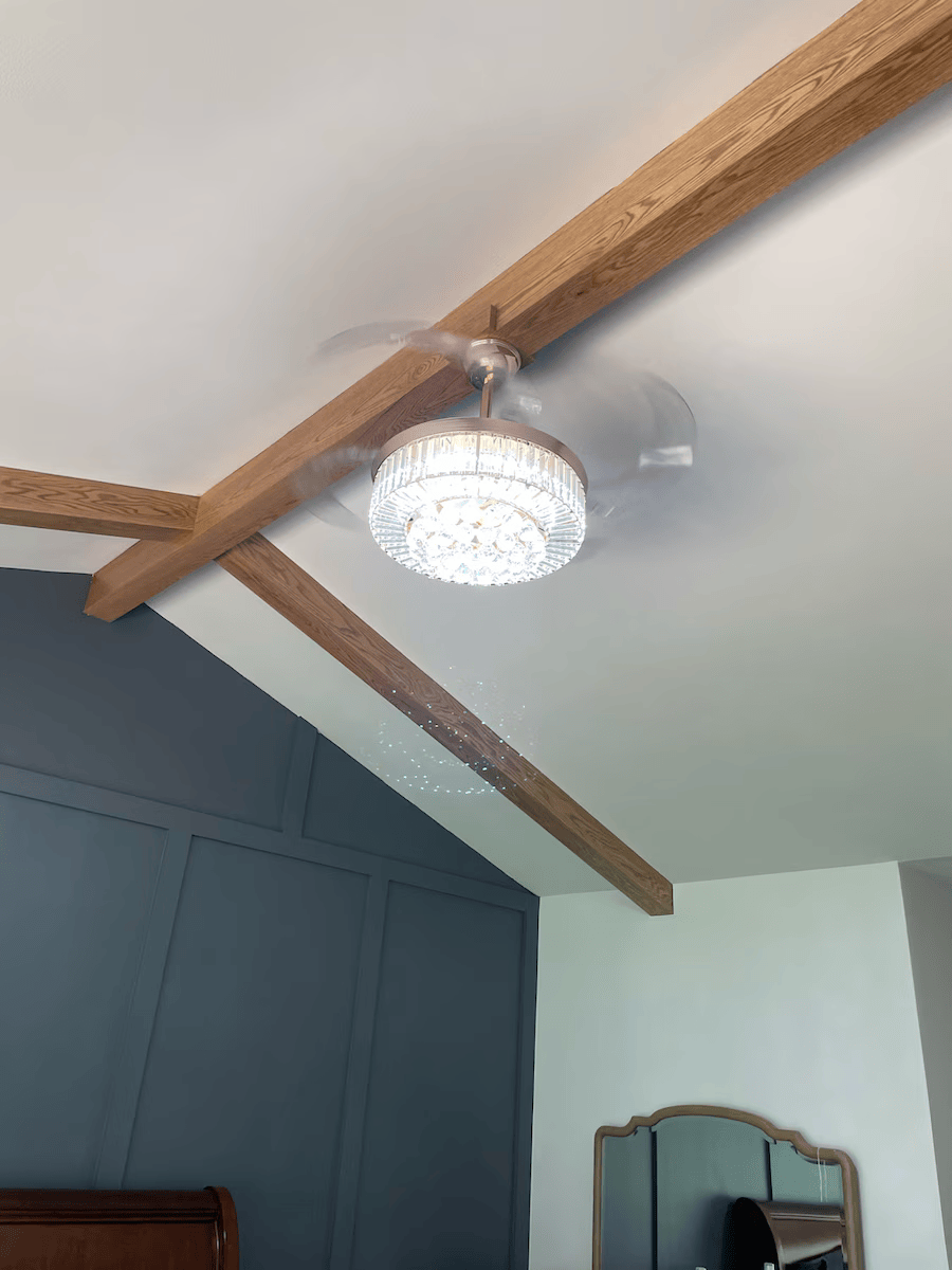 A bedroom with a ceiling fan and a mirror