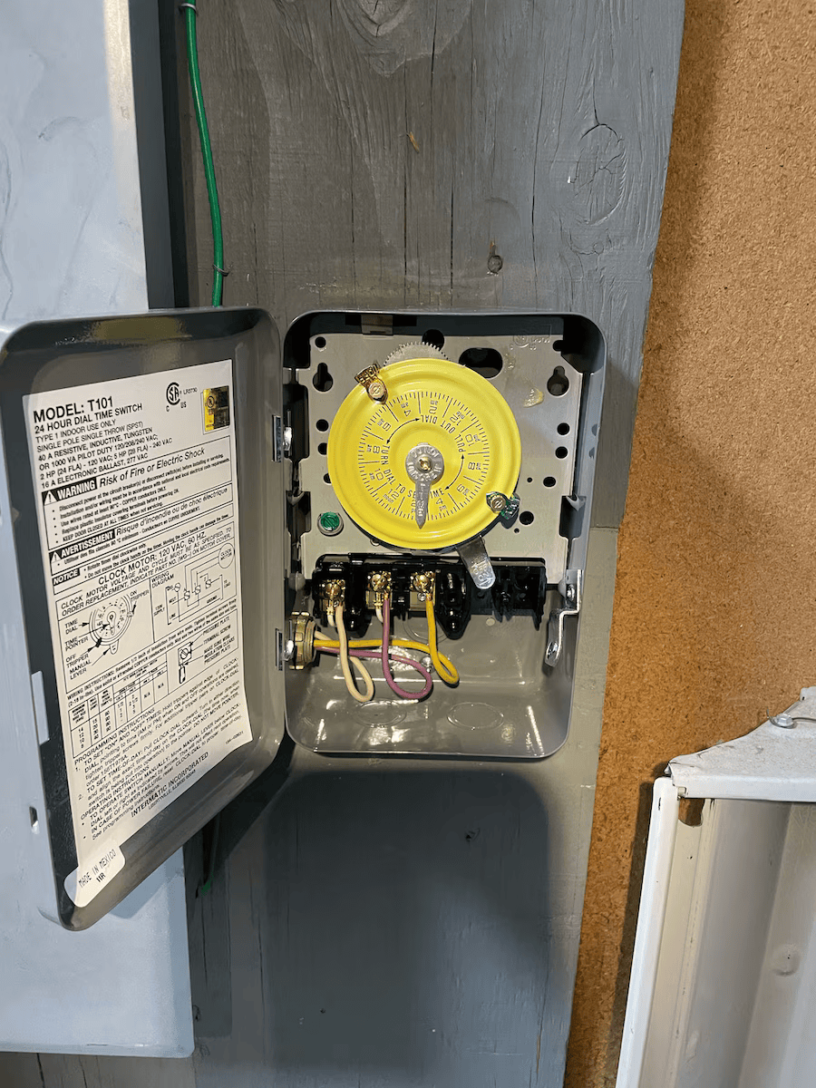 A close up of a timer box on a wall with the door open.