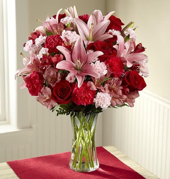 A vase filled with red and pink flowers on a table
