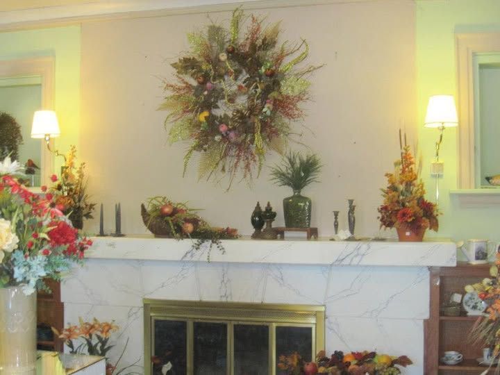 A living room with a fireplace and flowers on the mantle