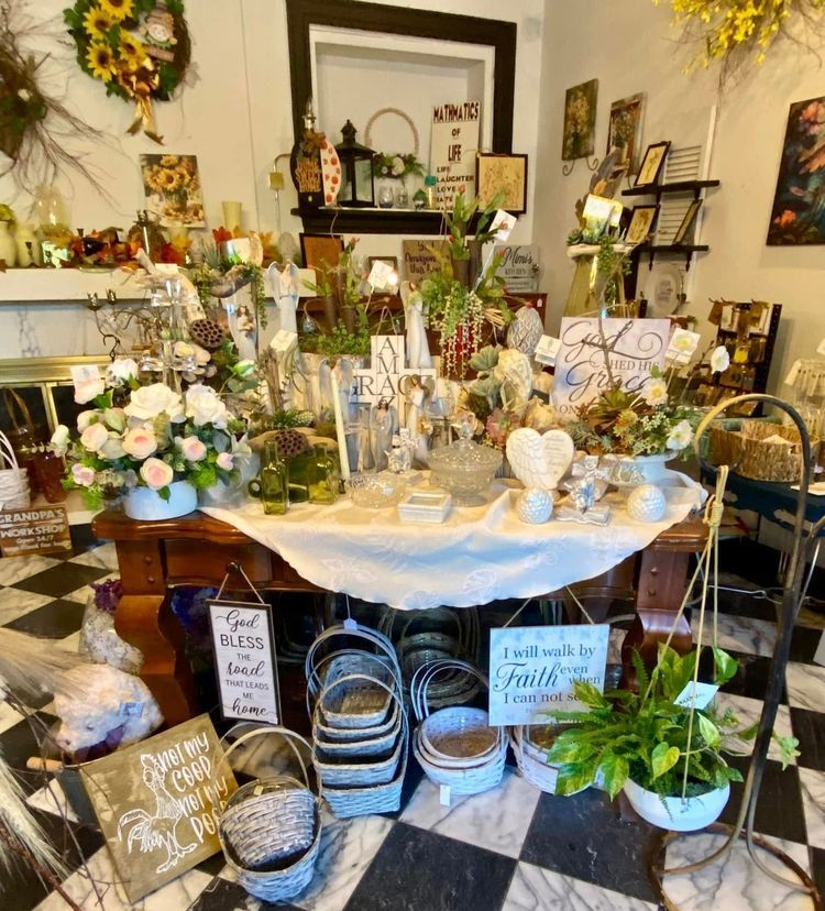 Floral shop interior with table display of flowers and decor, baskets, black and white checkered floor.