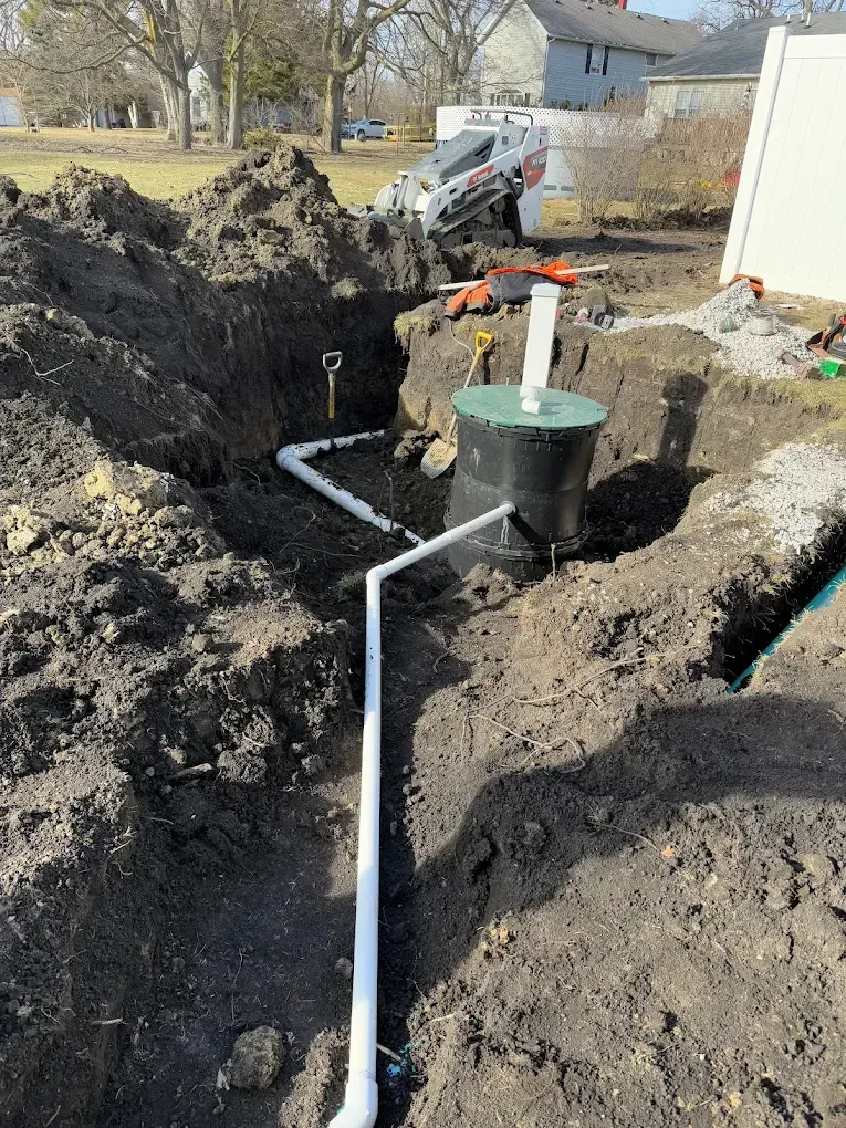 Construction site with an installed septic tank, white pipes, and excavation work.