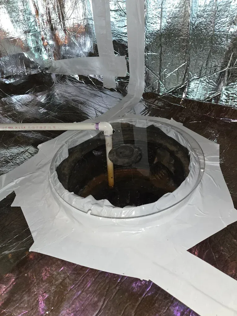 Circular opening in a dark surface, with piping and insulation tape around the edges.