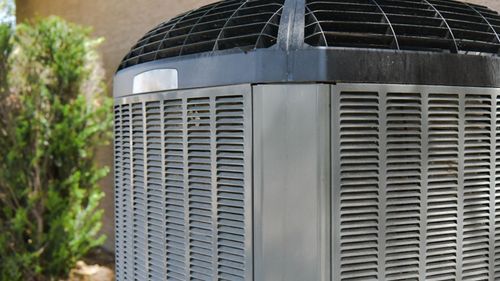 A large air conditioner is sitting outside of a building.