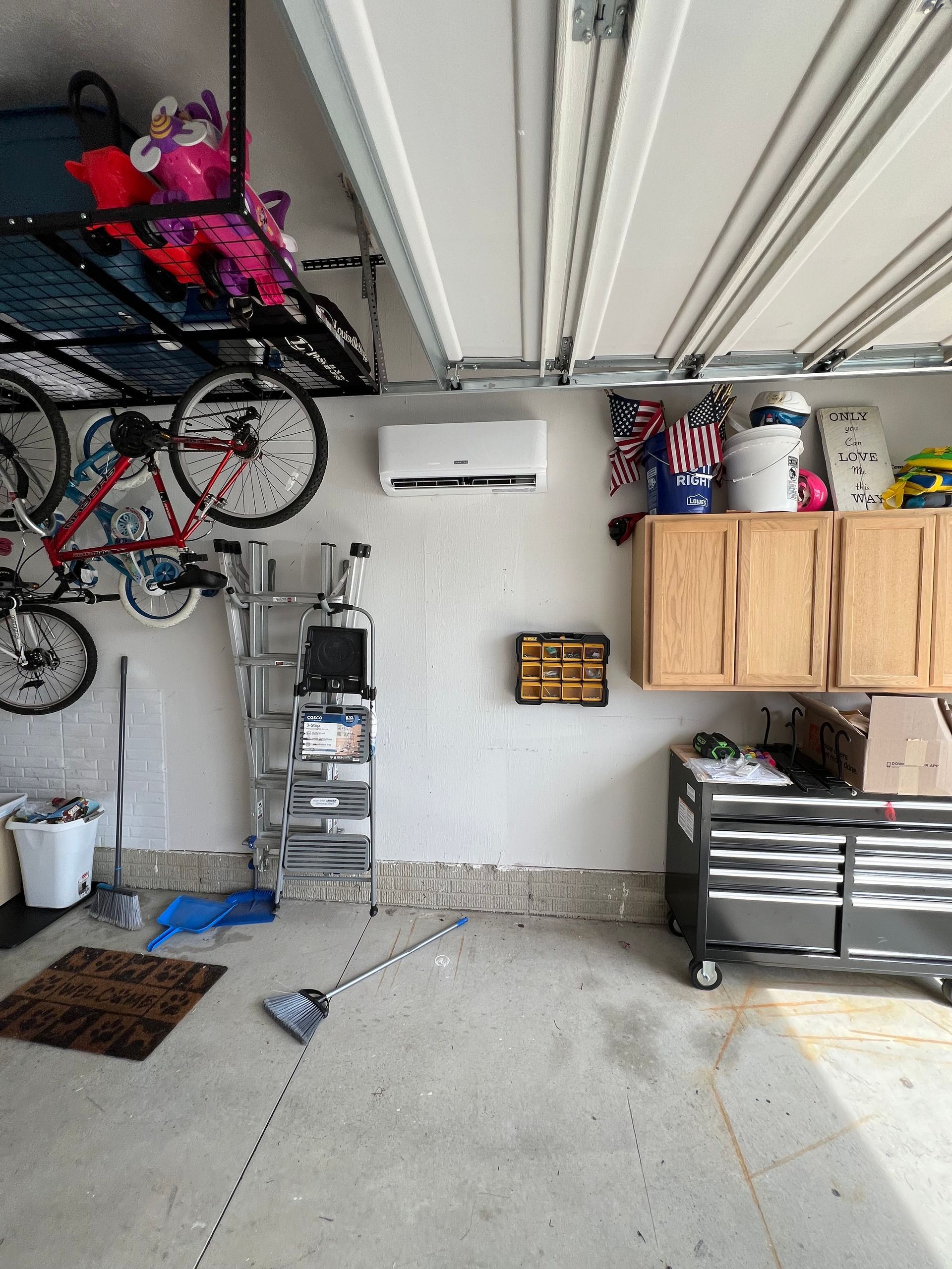 A garage with a bicycle hanging from the ceiling and a ladder.
