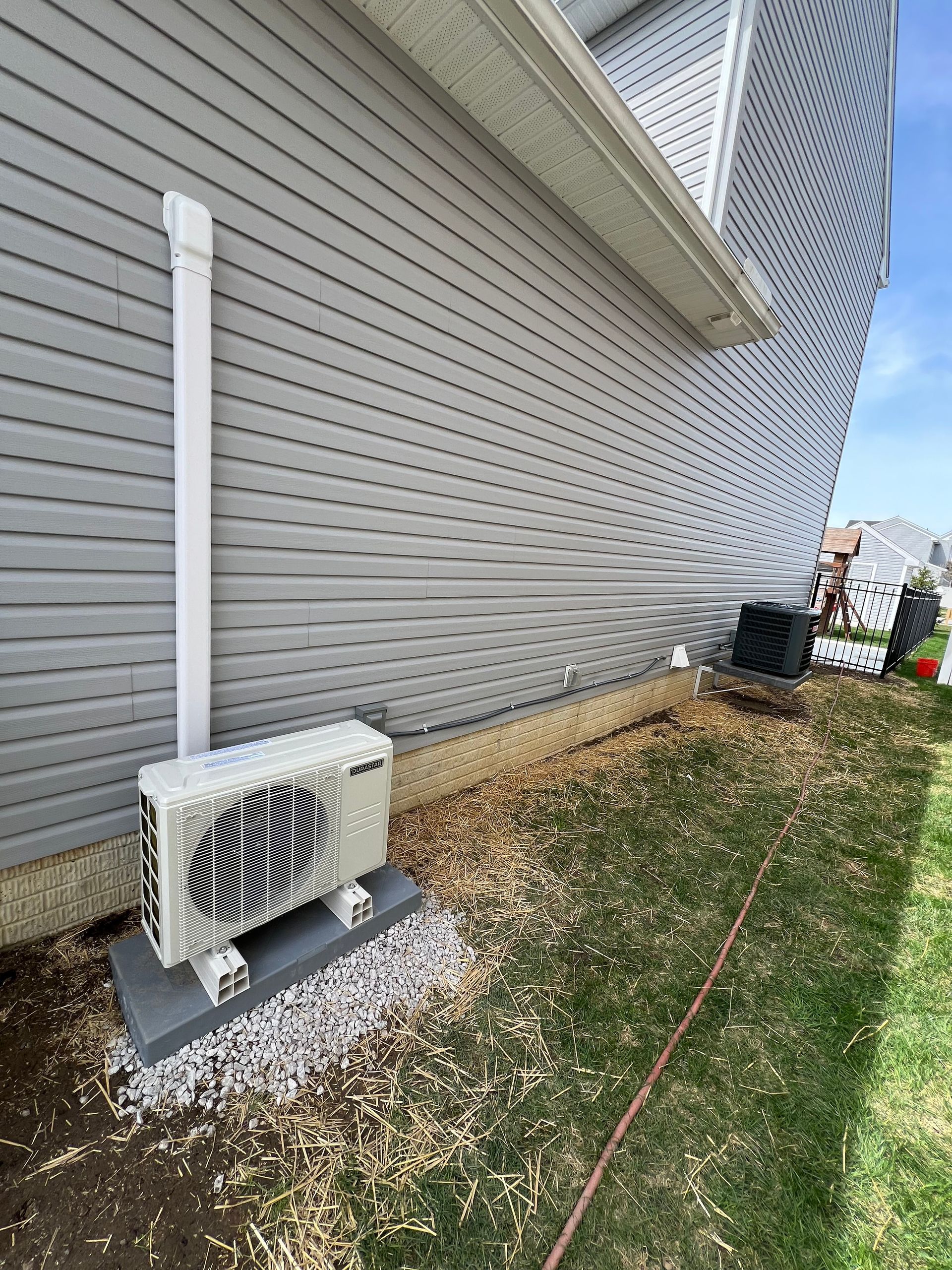 A white air conditioner is sitting on the side of a house.