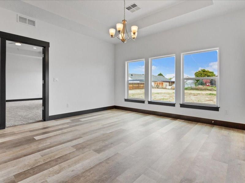 An empty living room with three windows and a chandelier.