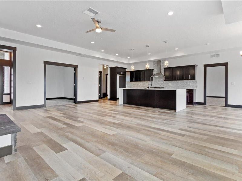 A large empty room with hardwood floors and a ceiling fan