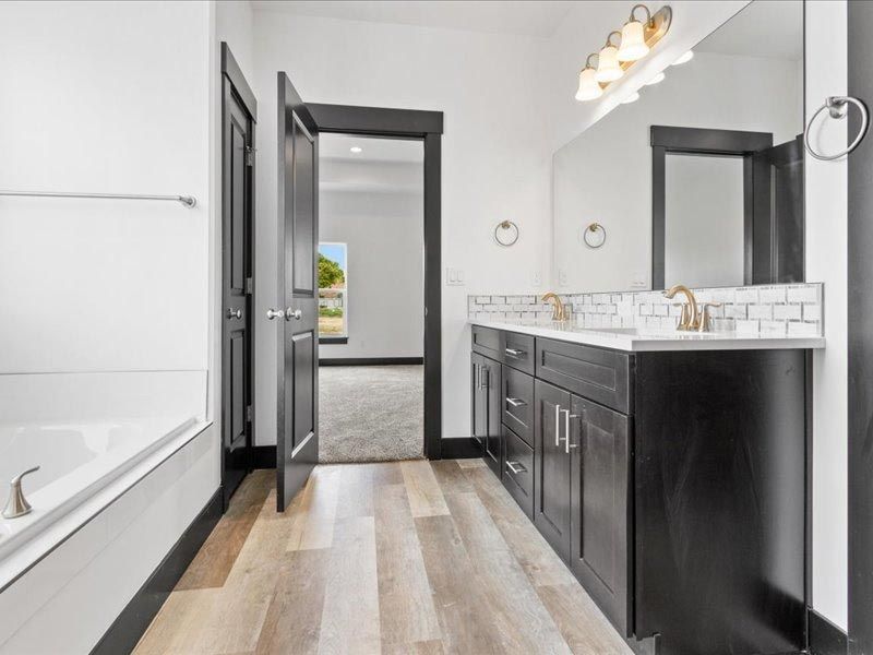 A bathroom with two sinks , a tub and a mirror.