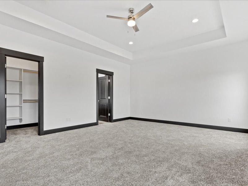An empty bedroom with a ceiling fan and a walk in closet.