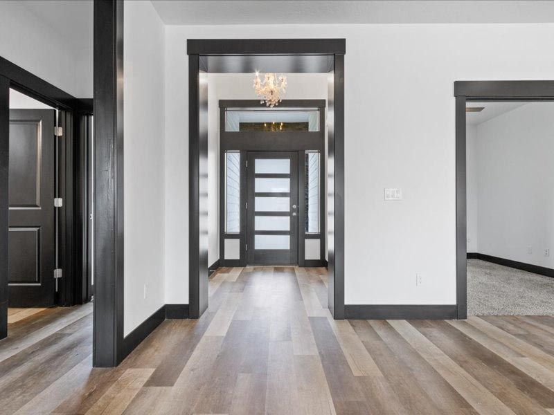 A hallway in a house with hardwood floors and a black door.