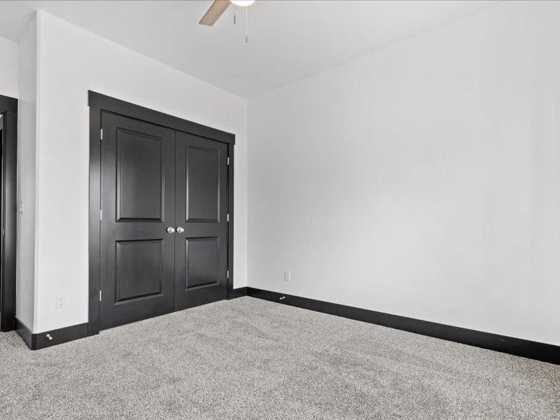 An empty bedroom with a ceiling fan and a large closet.