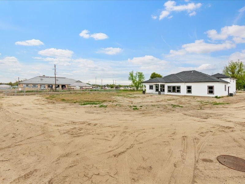 A white house is sitting in the middle of a dirt field.