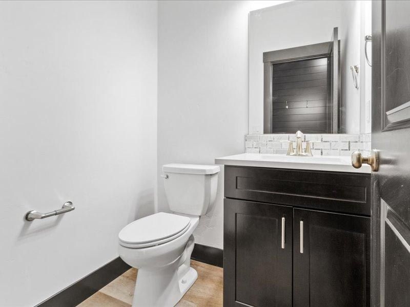 A bathroom with a toilet , sink and mirror.