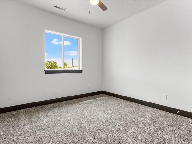 An empty bedroom with a window and a ceiling fan.