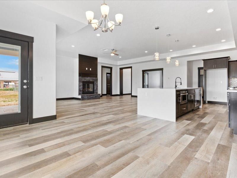 A living room with hardwood floors , a kitchen , and a fireplace.