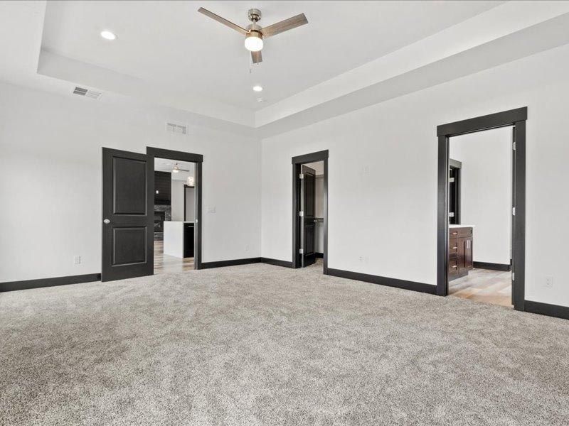 An empty room with a ceiling fan and a carpeted floor.