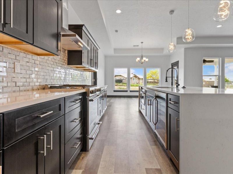 A kitchen with black cabinets and stainless steel appliances and a large island.