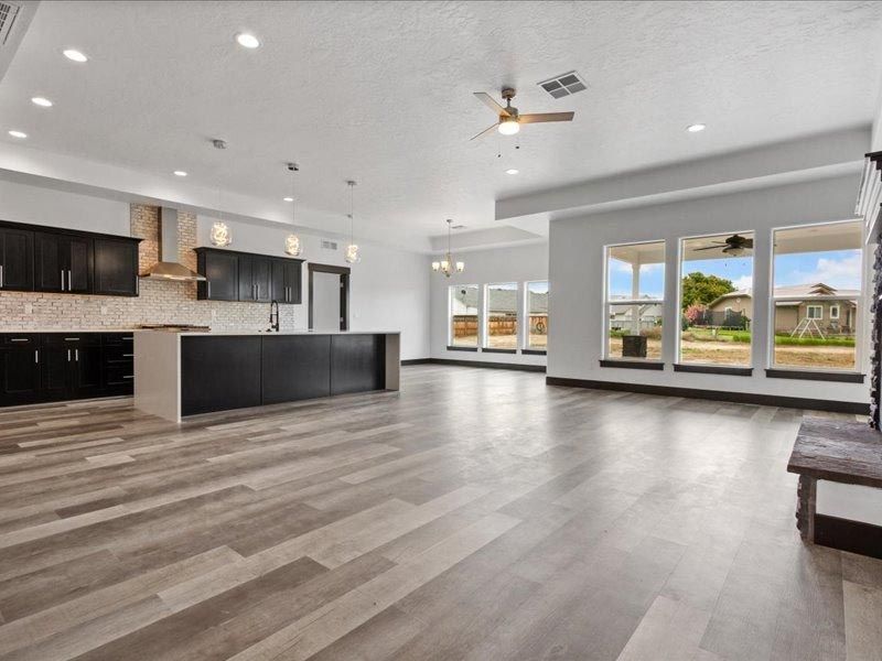 A large empty room with hardwood floors and a ceiling fan
