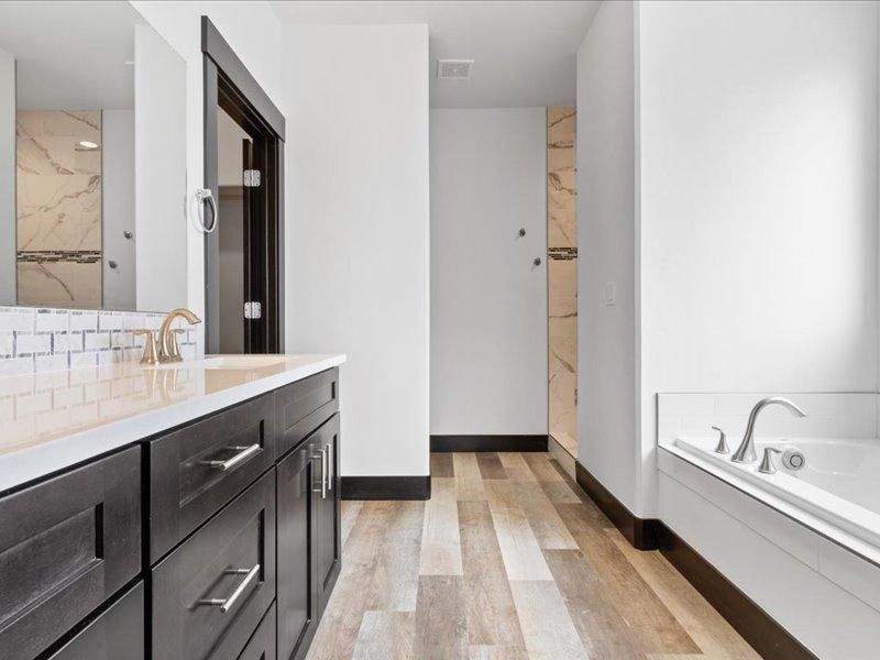 A bathroom with a tub , sink and mirror.
