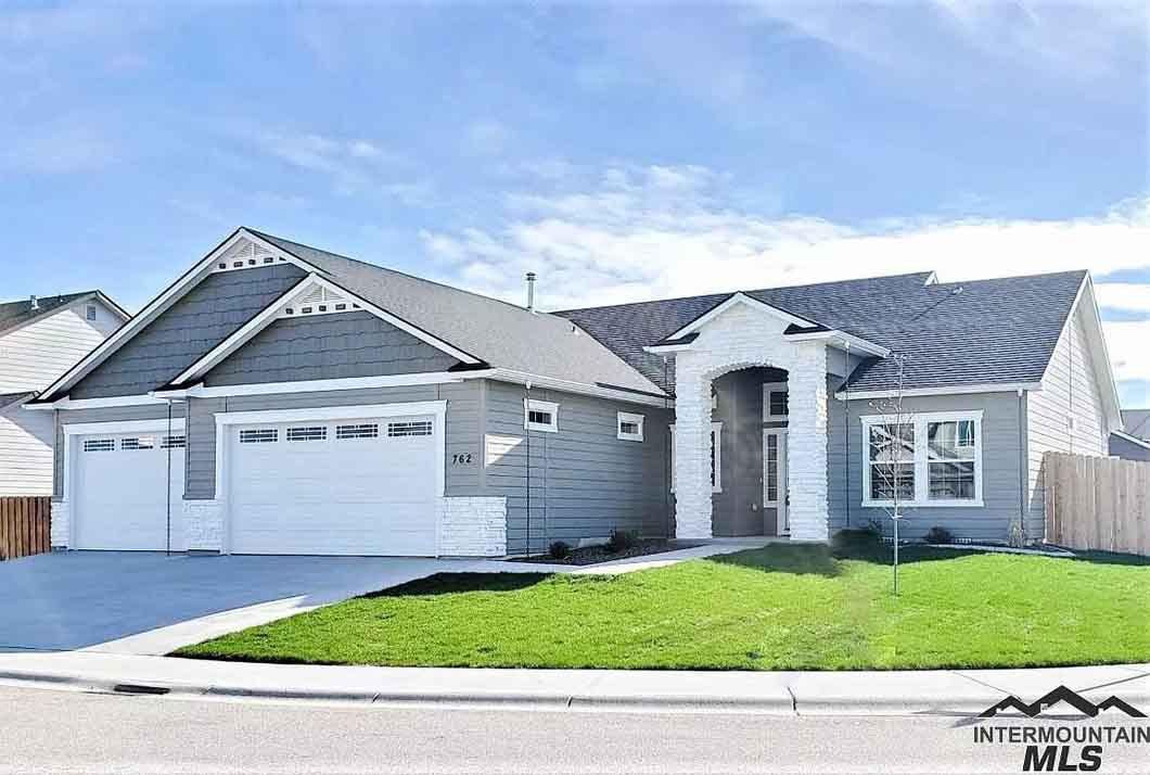 A large gray and white house with a white garage door is for sale.
