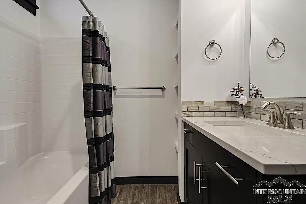 A bathroom with a tub , sink , mirror and shower curtain.
