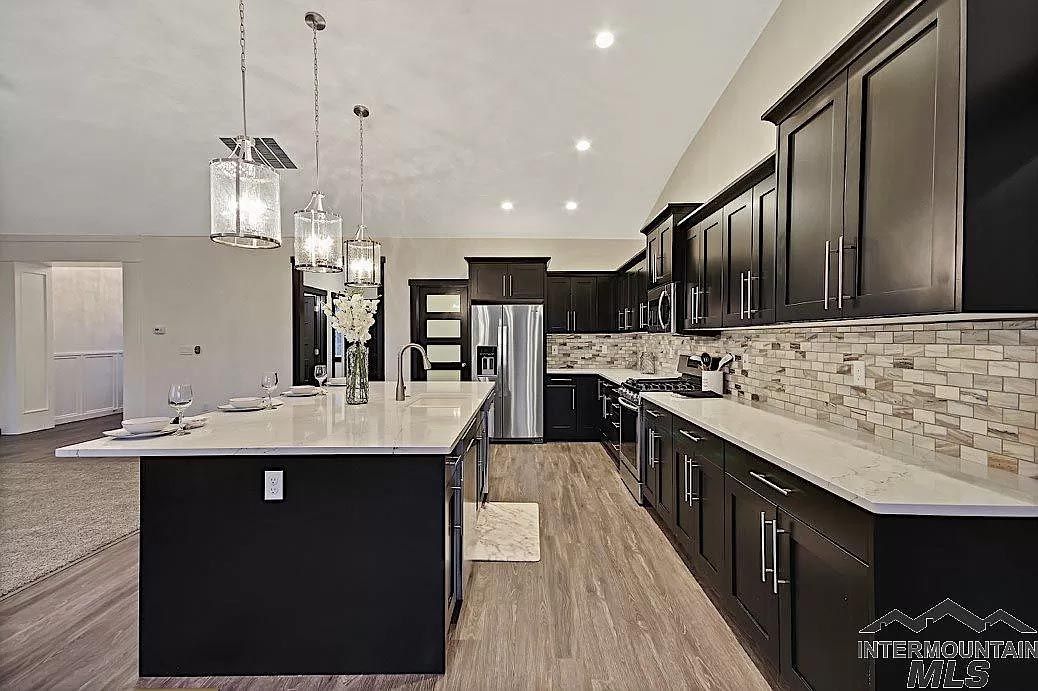 A kitchen with black cabinets , stainless steel appliances , and a large island.