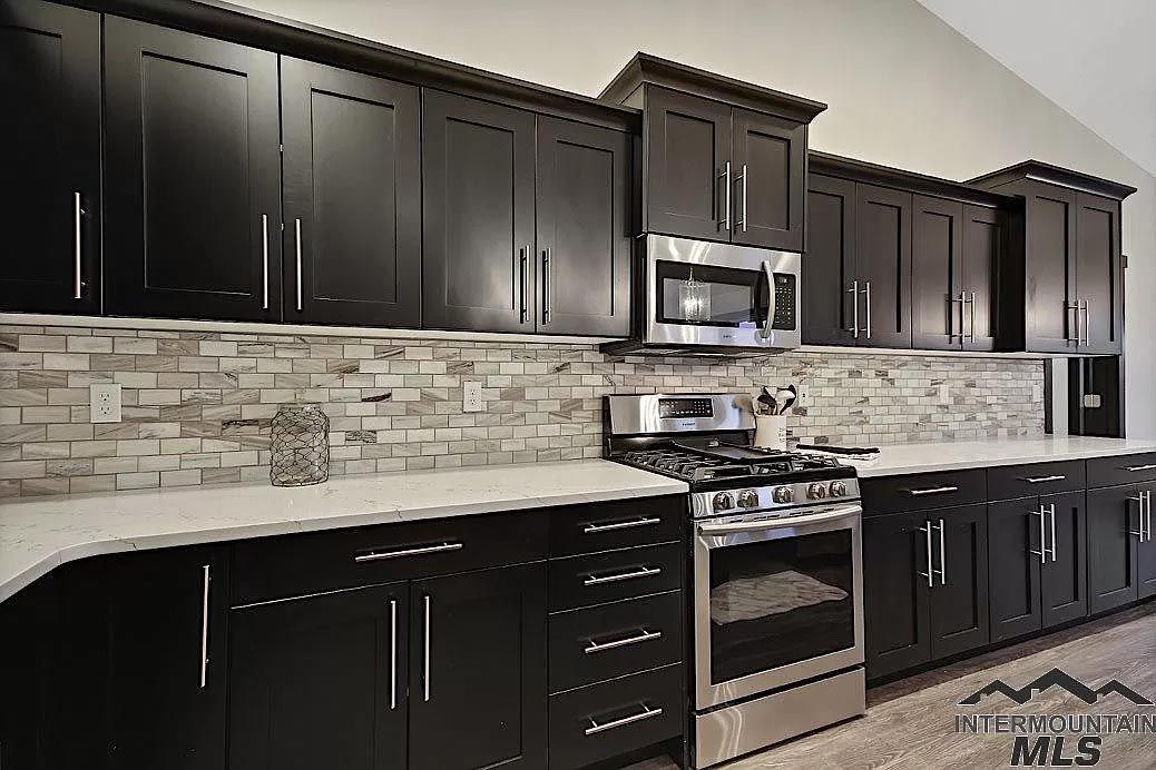 A kitchen with black cabinets and stainless steel appliances.