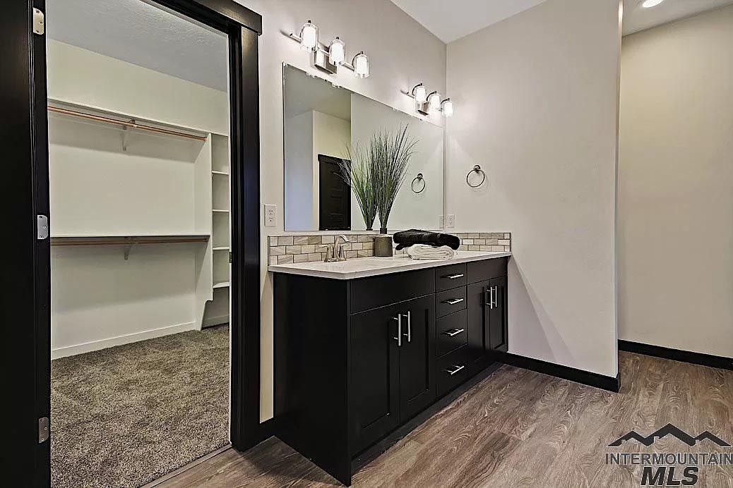 A bathroom with two sinks , a large mirror and a walk in closet.
