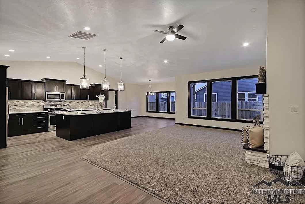 A large empty room with a kitchen , living room , and ceiling fan.