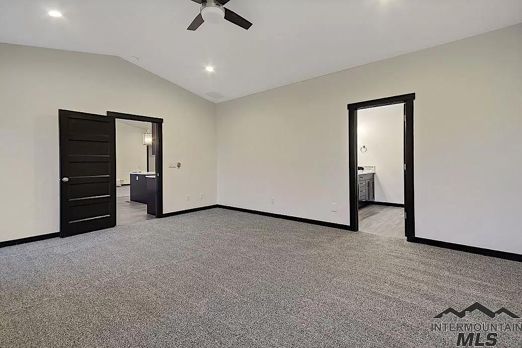 An empty room with a ceiling fan and a carpeted floor.