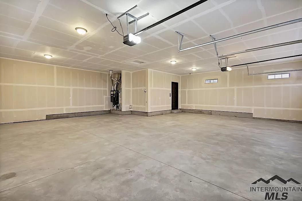 An empty garage with a garage door open and a ceiling fan.