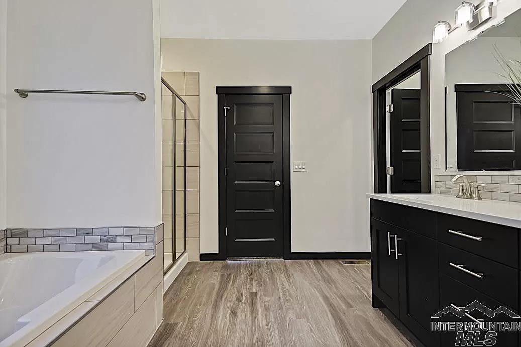 A bathroom with a tub , sink , mirror and shower.