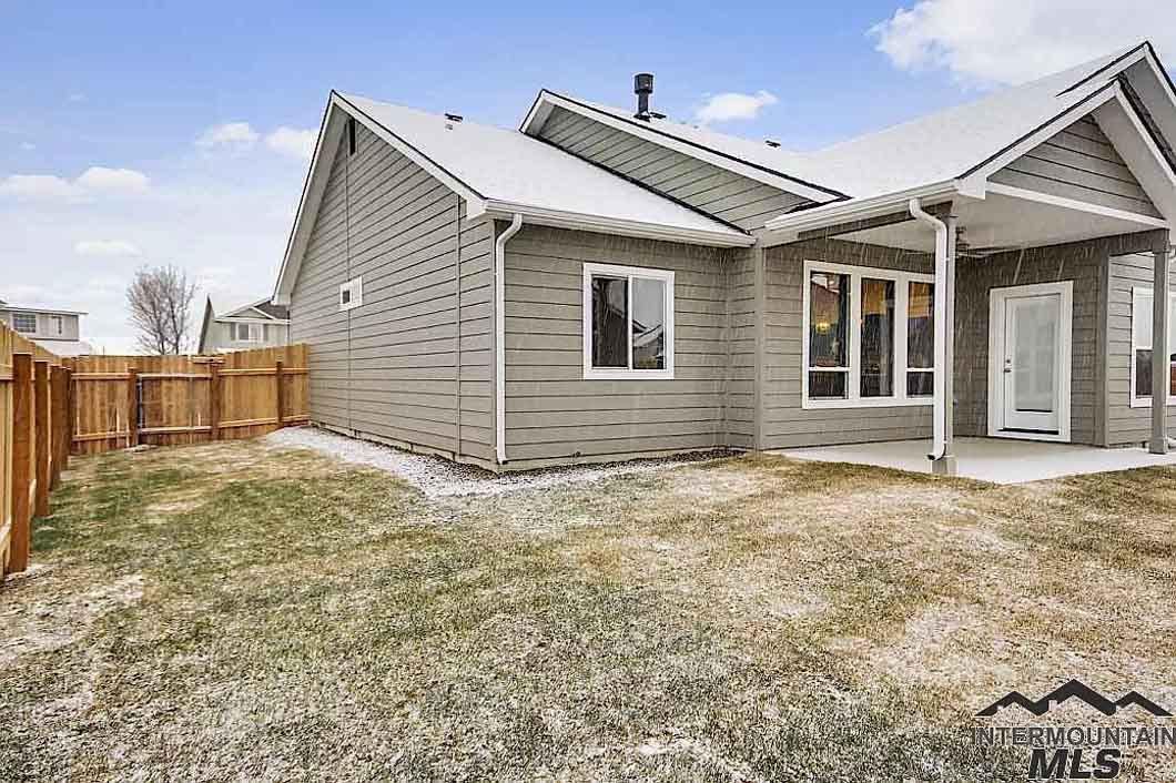 The backyard of a house with a fence and a lot of grass.